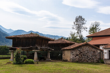Fototapeta na wymiar Hórreo, traditional granary from the North of Spain, built in wood and stone on four pillars that raise the horreo from the floor. Surrounded by traditional stone houses. Asturias, North Spain