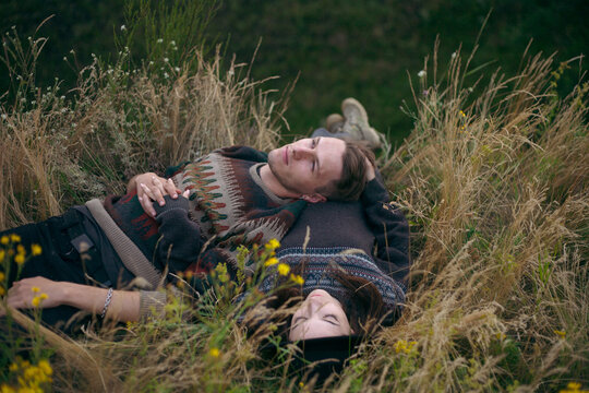 a girl and a guy lie in the grass