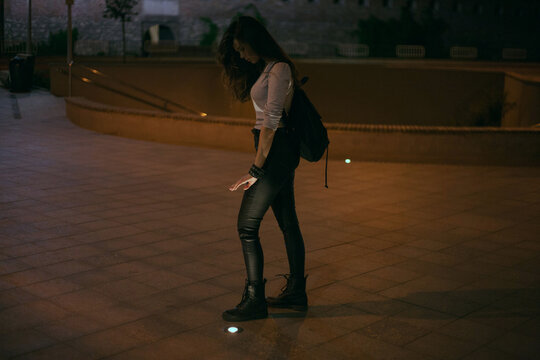 girl stands on the street and catches light from the streetlights in her hands