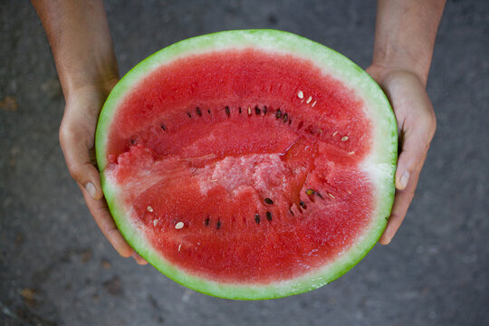 watermelon cut in half in hands