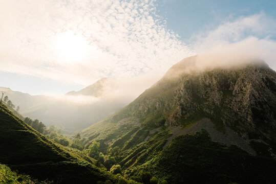 Amazing landscape of highlands surrounded by fog in morning on background of blue cloudy sky