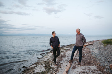Father and grown son talking together on the beach.