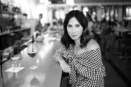 Portrait of an attractive woman sitting at a bar with a drink