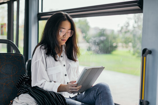 Asian woman in a transport public, with tablet at morning.