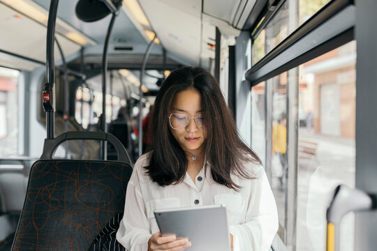 Asian woman in a transport public, with tablet at morning.