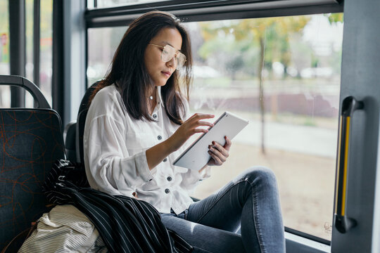 Asian woman in a transport public, with tablet at morning.