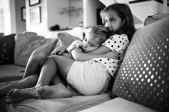 Brother holding on to his sister while watching something scary on television