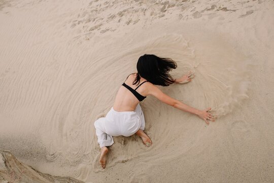 Unrecognizable dancer splashing sand on beach