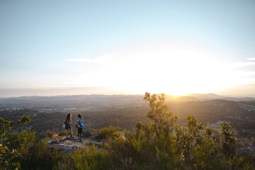 Mother and daughter hiking together at sunset.