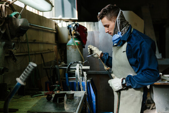 Man using a blowtorch in a foundry