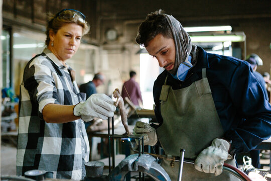 Sculptor and welder working on a piece of bronze in a foundry