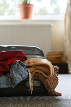Overflowing touristic suitcase on floor in room