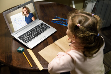 Kid virtual learning with teacher by laptop, tutor teaches preschool child during quarantine due to...