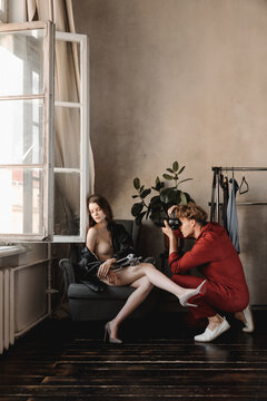 Young man taking photos of sensual model in cozy room