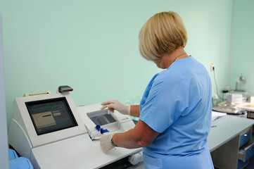 Lab technician performing analysis of blood samples with gas-electrolyte analyzer