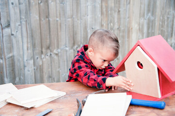 Dad and young son doing a birds house project together at home during lockdown, having lots of fun 