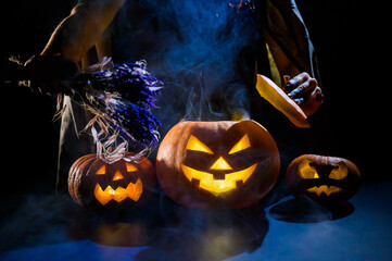 Witch casts a spell on a steaming pumpkin in the dark on Halloween