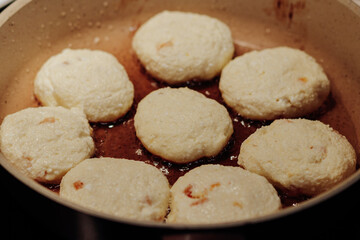 Cooking process of delicious fried syrniki close-up in the pan. Traditional in Ukraine, Belarus and Russia quark pancakes. Selective focus.