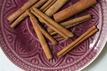 Macro image of cinnamon sticks on purple plate