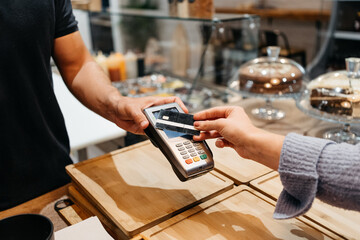 Detail of a client hands paying with the credit card at a restaurant