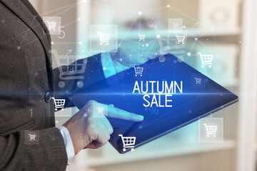 Young person makes a purchase through online shopping application with AUTUMN SALE inscription