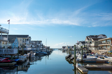 A View of a Canal With Boats and Houses on Each Side on a Clear Blue Sky With Gorgeous Clouds