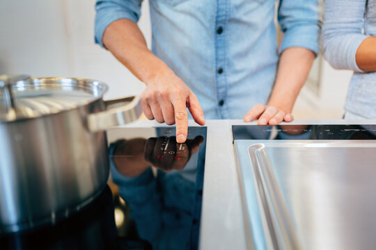 Crop man turning on stove under saucepan