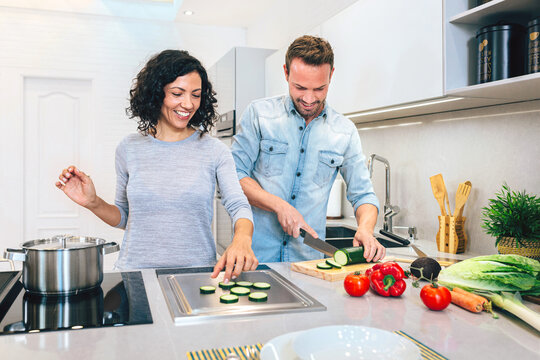 Couple cutting zucchini in kitchen