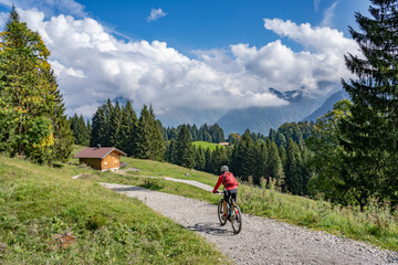Fototapeta na wymiar nice senior woman riding her electric mountain bike in the Allgau Alps near Oberstdorf, Bavaria, Germany