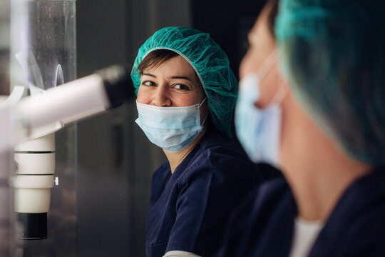 Biologists working on microscope in IVF laboratory