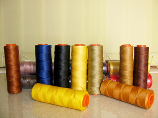 A set of multi-colored thick yellow, brown, black, blue threads for sewing leather products.