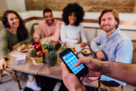 Waiter with smartphone serving customers in cafe