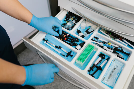 Faceless worker opening drawer with equipment for dental care