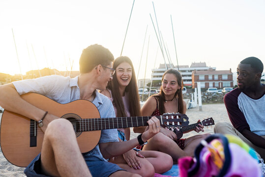 Multiethnic friends singing songs on summer beach