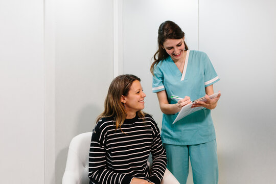 Nurse taking notes on paper besides a patient