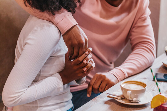 Faceless ethnic couple on date in cafe