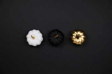 Minimal Halloween holiday concept. Halloween decoration, golden, black and white pumpkins. Flat lay, top view, copy space