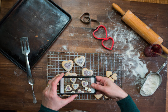 Woman's hands taking pictures of heart shaped cookies