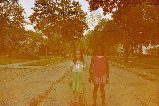 Caucasian and black gils holding hands in the street