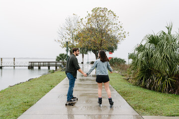 Young couple on skates and longboard on a pier