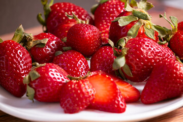 Strawberries on a white square plate on a wooden table in a rustic setting