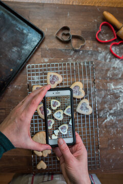Woman's hands taking pictures of heart shaped cookies