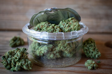 Cannabis in an open plastic jar with a pop-top tin lid - close up