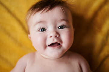 Cute baby lying on blanket and smiling at camera