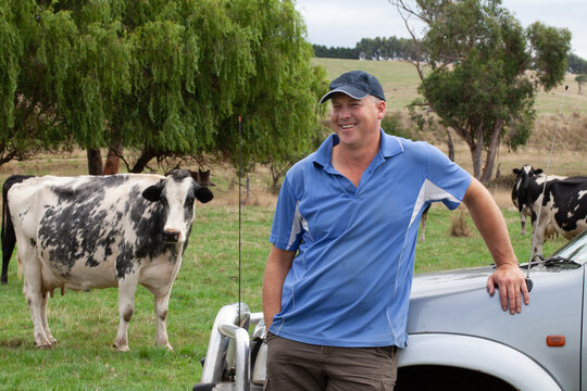 Dairy farmer inspecting his herd in the paddock leaning against his 4WD