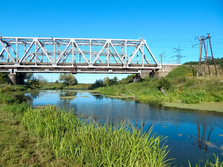 Steel railway bridge over the river, countryside landscape, sunny day