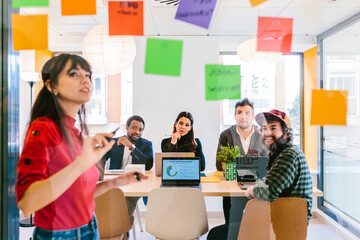 Woman writing on notes sharing ideas with colleagues