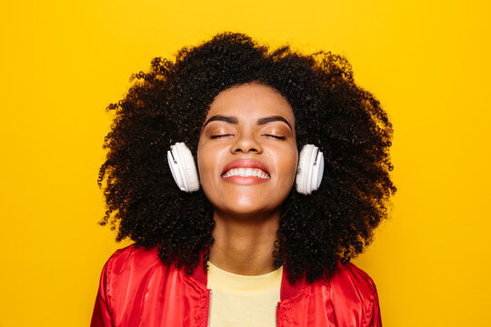 Beautiful afro woman listening to music with white headphones