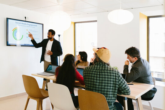 Black male presenting report on display to coworkers