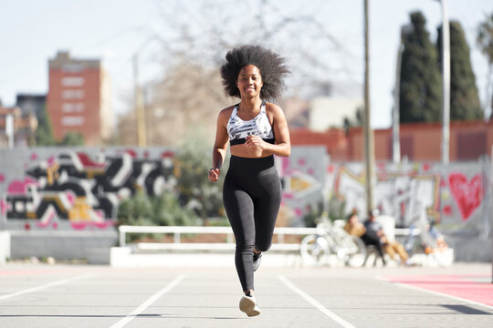 Active fit woman running on sports ground